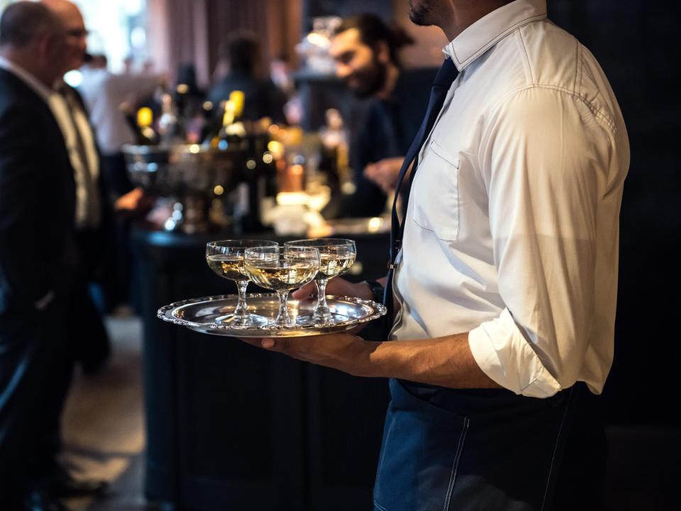 Wedding vendor server holding a plate of drinks at event