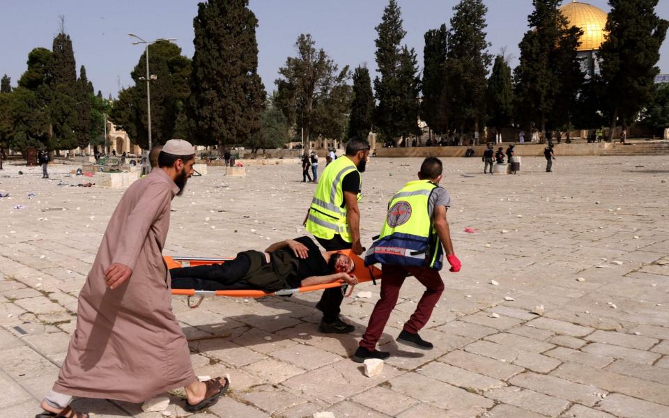 Palestinian medics evacuate a wounded protester amid clashes with Israeli security forces at Jerusalem's Al-Aqsa mosque compound - AHMAD GHARABLI/AFP via Getty Images