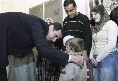 Syria's President Bashar al-Assad speaks with children during his visit to displaced Syrians in the town of Adra in the Damascus countryside March 12, 2014, in this handout photograph released by Syria's national news agency SANA. REUTERS/SANA/Handout via Reuters