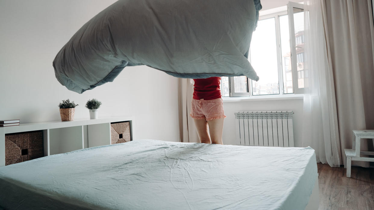  A woman prepares to put a comforter on a freshly cleaned mattress. 