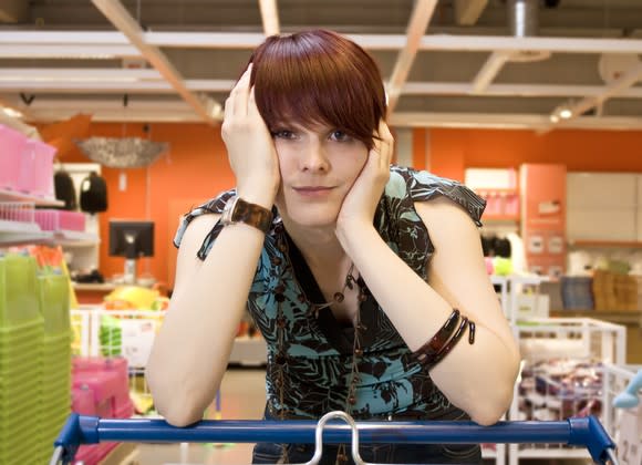 Woman resting on shopping cart in frustration