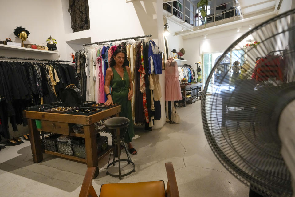 Floriana Peroni walks in her vintage clothing store in downtown Rome, that was forced to shut down for a week by a truck of rented generators blocking her door as it fed power to the central Roman neighborhood hit by a localized blackout, in central Rome, Tuesday, July 25, 2023. Rising global temperatures are elevating air conditioning from a luxury to a necessity in many parts of Europe, which long has had a conflictual relationship with energy-sucking cooling systems deemed by many a U.S. indulgence. (AP Photo/Andrew Medichini)