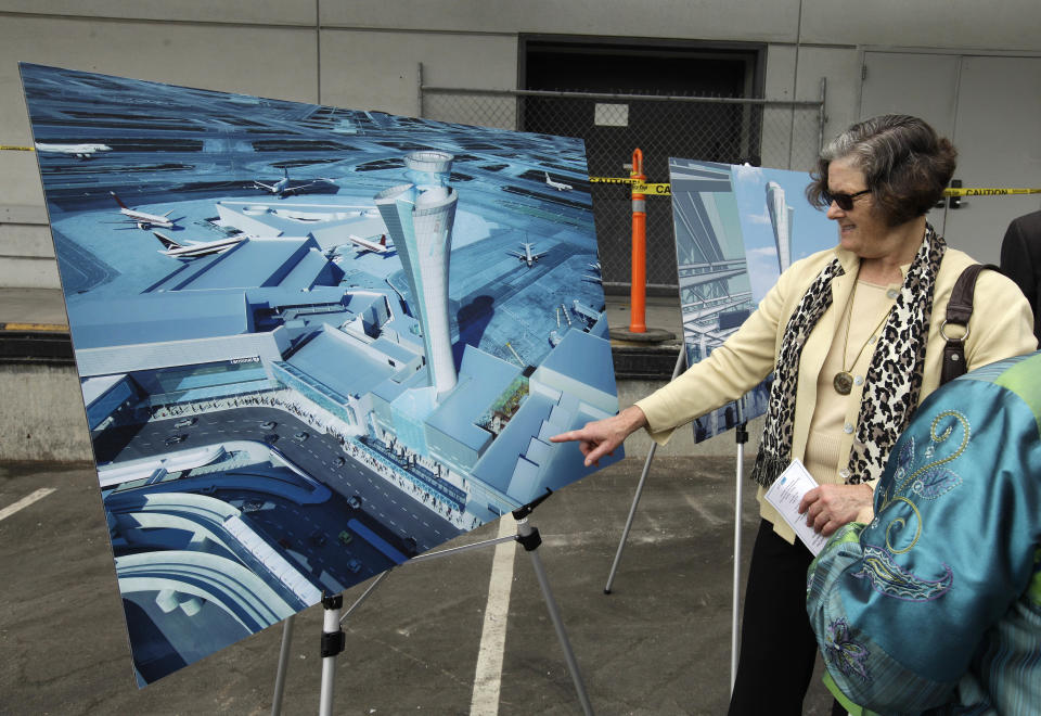 Kathryn Luhe, a deputy city attorney, looks over an artist's drawings during a groundbreaking ceremony for a new traffic control tower at San Francisco International Airport Monday, July 9, 2012 in San Francisco. The airport is getting a new control tower with a unique design that resembles a torch, not the traditional lollipop shape of other towers. The FAA expects to start using the 221-foot tall facility in 2015. (AP Photo/Eric Risberg)