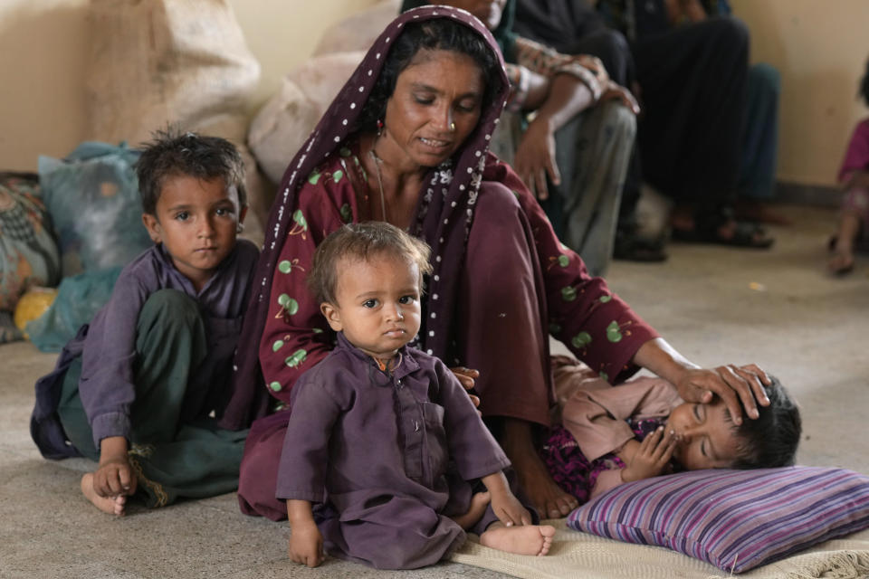 A woman takes care of her child as she with other families take shelter in a school after fleeing from their villages of costal areas due to Cyclone Biparjoy approaching, in Gharo near Thatta, a Pakistan's southern district in the Sindh province, Wednesday, June 14, 2023. In Pakistan, despite strong winds and rain, authorities said people from vulnerable areas have been moved to safer places in southern Pakistan's districts. With Cyclone Biparjoy expected to make landfall Thursday evening, coastal regions of India and Pakistan are on high alert. (AP Photo/Fareed Khan)