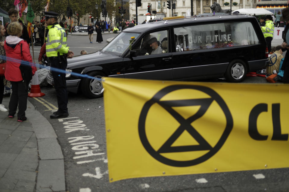 Extinction Rebellion climate change demonstrators block a road with a hearse where Trafalgar Square joins Whitehall in London, Tuesday, Oct. 8, 2019. Hundreds of climate change activists camped out in central London on Tuesday during a second day of world protests by the Extinction Rebellion movement to demand more urgent actions to counter global warming. (AP Photo/Matt Dunham)