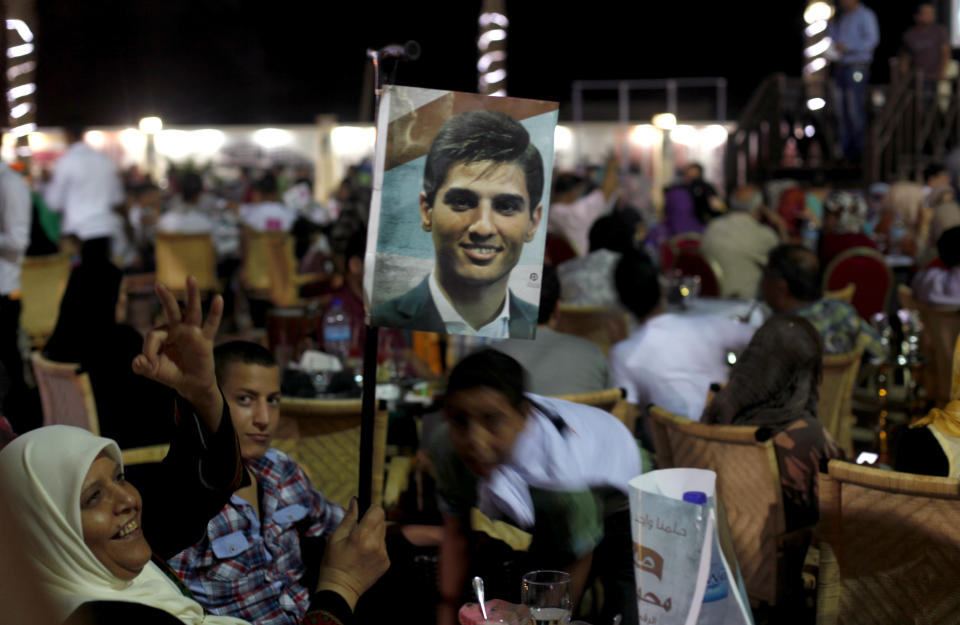 A Palestinian woman waves a picture of Palestinian singer Mohammed Assaf while watching the contestant perform in a regional TV singing contest, in Gaza City, Saturday, June 22, 2013. Palestinians relished a rare moment of pride and national unity Saturday after the 23-year-old wedding singer from a refugee camp in the Gaza Strip won “Arab Idol,” a regional TV singing contest watched by millions of people. (AP Photo/Hatem Moussa)