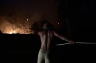 A man uses a water hose during a wildfire in Adames area, in northern Athens, Greece, Tuesday, Aug. 3, 2021.Thousands of people fled their homes north of Athens on Tuesday as a wildfire broke out of the forest and reached residential areas. The hurried evacuations took place just as Greece grappled with its worst heat wave in decades. (AP Photo/Michael Varaklas)