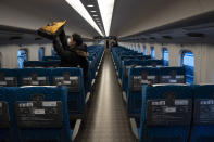 A traveler places his bag in an overhead luggage rack in a bullet train bound for Kyoto and Osaka at Tokyo Station in Tokyo, March 17, 2020. (AP Photo/Jae C. Hong)