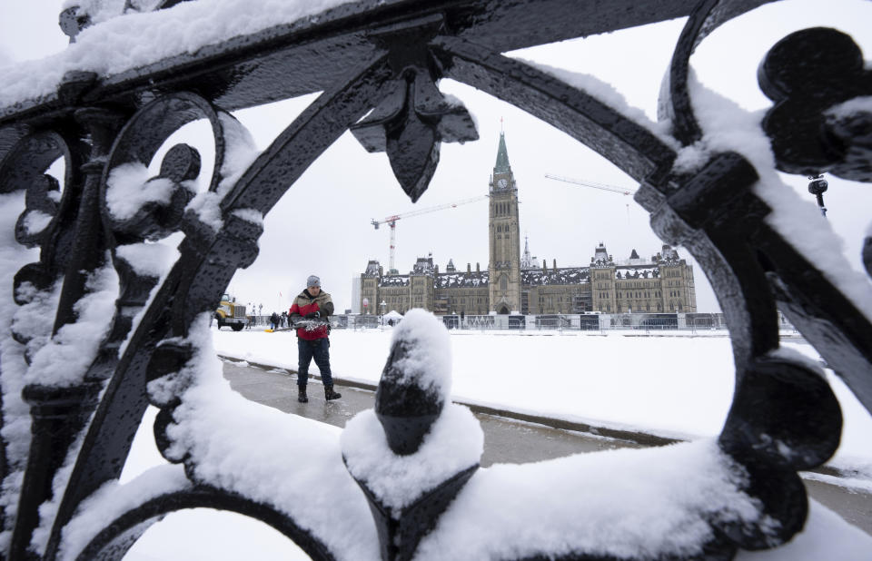 A worker prepares a pathway on Parliament Hill following a snow fall, Monday, Dec. 4, 2023., in Ottawa, Ontario. (Adrian Wyld/The Canadian Press via AP)