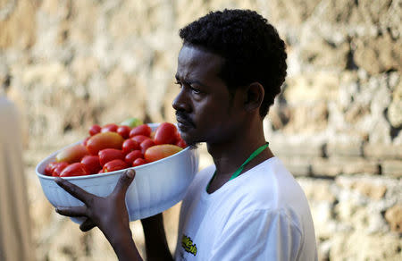 A migrant carries tomatoes at a makeshift camp in Via Cupa (Gloomy Street) in downtown Rome, Italy, August 1, 2016. REUTERS/Max Rossi