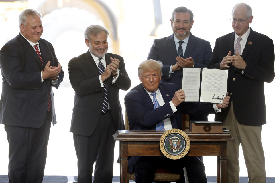 President Donald Trump holds up a permit for energy development after signing it during a visit to the Double Eagle Energy Oil Rig, Wednesday, July 29, 2020, in Midland, Texas. Sen. Ted Cruz, R-Texas, stands rear, second from right. (AP Photo/Tony Gutierrez)