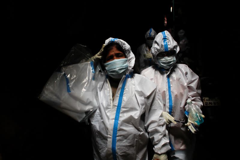 A health worker in personal protective equipment reacts as she and the rest of the team walk through an alley during a check up campaign for the coronavirus disease (COVID-19) at a slum area in Mumbai