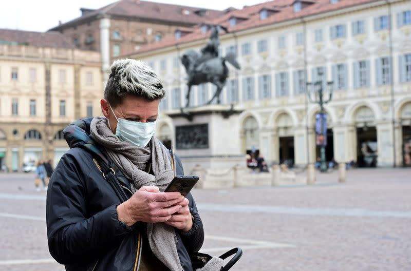 FILE PHOTO: Woman wearing a protective mask uses her mobile phone, as a coronavirus outbreak continues to grow in northern Italy, in Turin