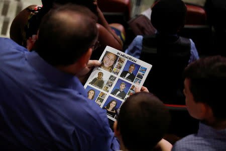 A man looks at pictures of the victims of the mass shooting in Parkland on the program during the graduation ceremony for students from the Marjory Stoneman Douglas High School, in Sunrise, Florida, U.S., June 3, 2018. REUTERS/Carlos Garcia Rawlins