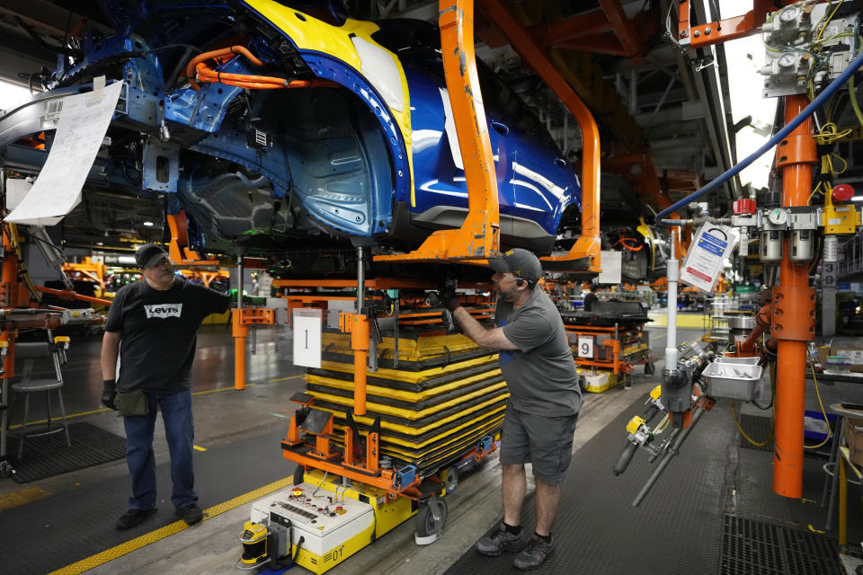 File - Assembly line workers Alfredo Gutierrez, left, and Ryan Pontillo attach an LG battery to a 2023 Chevrolet Bolt EV at the General Motors Orion Assembly, June 15, 2023, in Lake Orion, Mich. On Wednesday, the Labor Department reports on job openings and labor turnover for November. (AP Photo/Carlos Osorio)