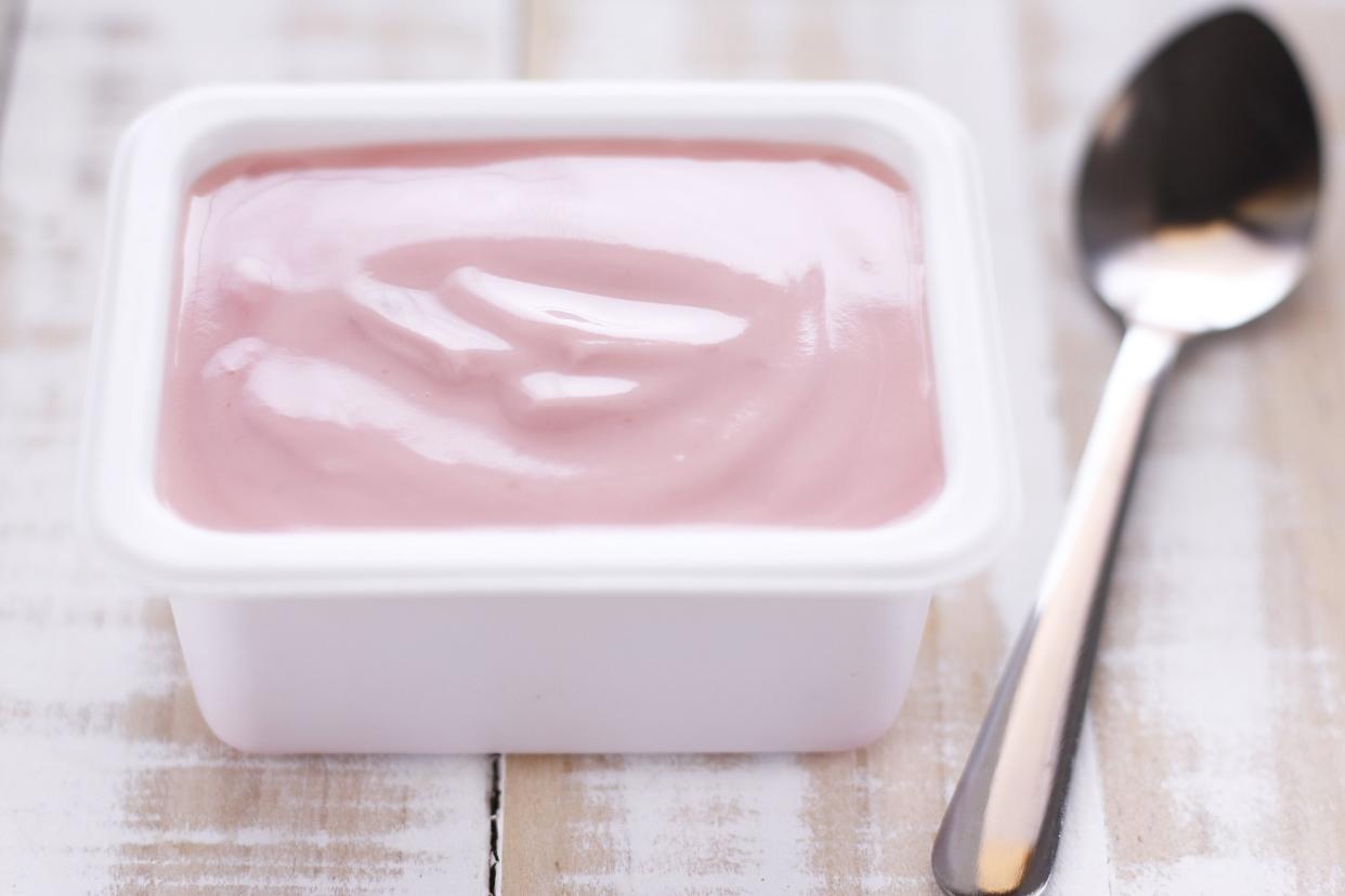 strawberry yogurt in white plastic cup with spoon