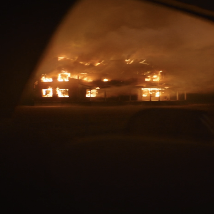 A burning building seen from the car window in the series