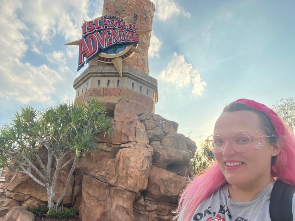 casey posing for a selfie with the islands of adventure sign at universal