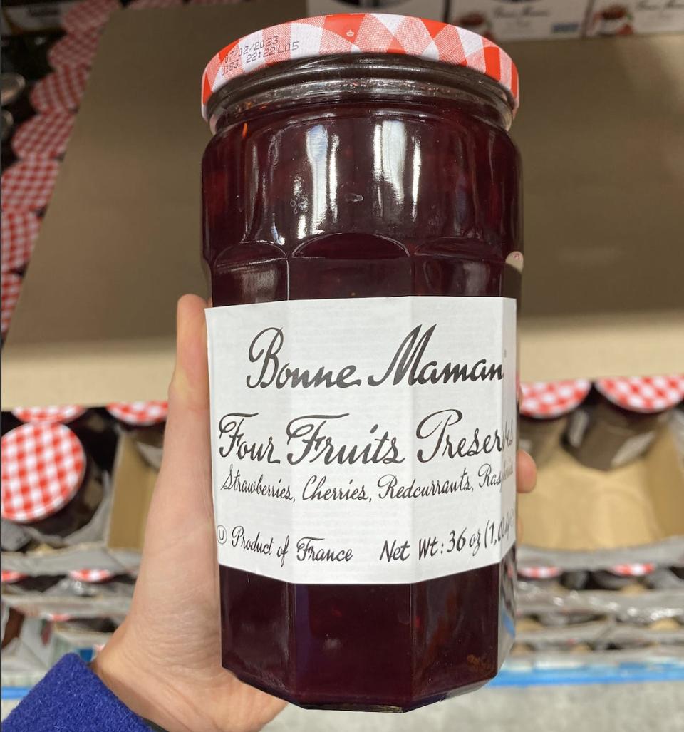 Hand holding jar of Bonne Mamam fruit preserves at Costco