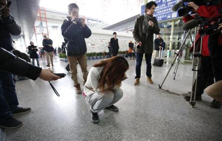 ournalists attempt to interview a woman who is the relative of a passenger on Malaysia Airlines flight MH370, as she crouches on the floor crying, at the Beijing Capital International Airport in Beijing March 8, 2014. REUTERS/Kim Kyung-Hoon