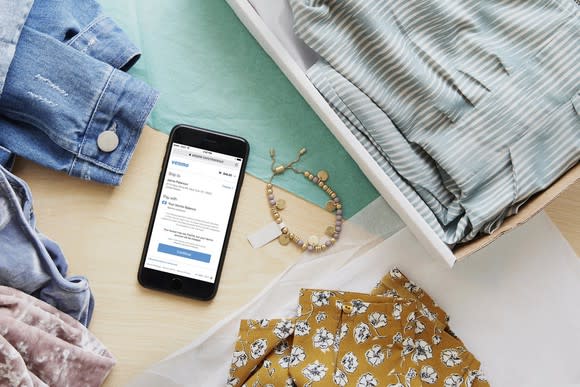 A phone with the Venmo app open, sitting on a table surrounded by clothing