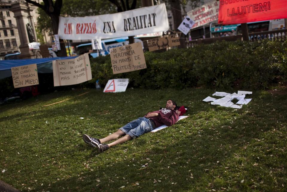 A demonstrator sleeps on the ground after he spent the night at the Catalunya square during a protest to mark the anniversary of the beginning of the "Indignados" movement in Barcelona, Spain, Sunday May 13, 2012. Spaniards angered by increasingly grim economic prospects and unemployment hitting one out of every four citizens protested in droves Saturday in the nation's largest cities, marking the one-year anniversary of a spontaneous movement that inspired similar anti-authority demonstrations across the planet. (AP Photo/Emilio Morenatti)