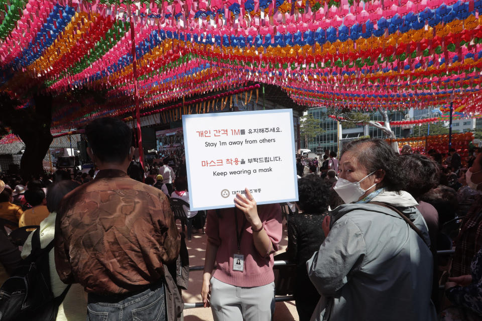 A Buddhist believer holds a notice about precautions against the new coronavirus during the Buddha's birthday ceremony at the Jogye temple in Seoul, South Korea, Saturday, May 30, 2020. This year a ceremony to celebrate the birth anniversary was put off from April 30 to May 30 due to the coronavirus. (AP Photo/Ahn Young-joon)