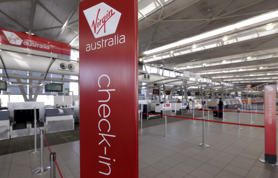 The Virgin Australia check-in counters are all but bare at Sydney Airport in Sydney, Wednesday, April 22, 2020. Virgin Australia is seeking bankruptcy protection, entering voluntary administration after a debt crisis worsened by the coronavirus shutdown pushed it into insolvency. (AP Photo/Rick Rycroft)
