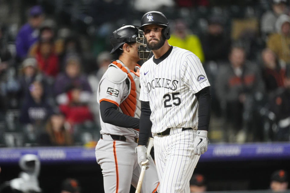 Colorado Rockies' Jacob Stallings, front, reacts after striking out against San Francisco Giants pitcher Camilo Doval as catcher Blake Sabol waits for play to resume in the ninth inning of a baseball game Tuesday, May 7, 2024, in Denver. (AP Photo/David Zalubowski)