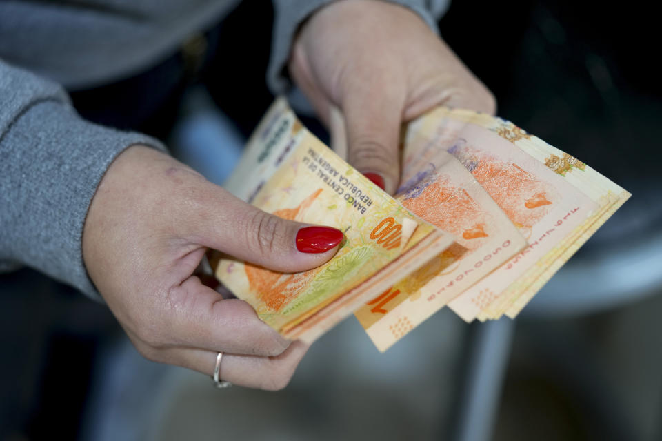 A shop worker counts Argentine pesos that Uruguayan Carolaine Sololuce used to pay for a pair of pants in Gualeguaychu in the Entre Rios province of Argentina, a few kilometers from the Uruguayan border, Friday June 30, 2023. Sololuce bought the pants for 9,000 Argentine pesos, or $18 on the black market. In Fray Bentos, the pants would have cost her $48. (AP Photo/Natacha Pisarenko)