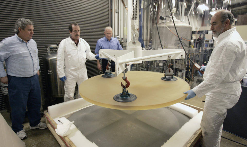 FILE - In this Jan. 7, 2008, file photo, Thirty Meter Telescope Project Scientist Jerry Nelson, left, and Telescope Optics Group Leader Eric Williams, third from left, inspect a 500 pound glass blank as it is removed from packing by Dave Hilyard, Chief Optician at University of California, right, and Brian Dupraw at the UC Observatory Optical Lab at the University of California at Santa Cruz, Calif. Astronomers across 11 observatories on Hawaii’s tallest mountain Mauna Kea have cancelled more than 2,000 hours of telescope viewing over the past four weeks because a protest blocked a road to the summit. Astronomers said Friday, Aug. 9, 2019, they will attempt to resume observations but in some cases won’t be able to make up the missed research. (AP Photo/Ben Margot, File)