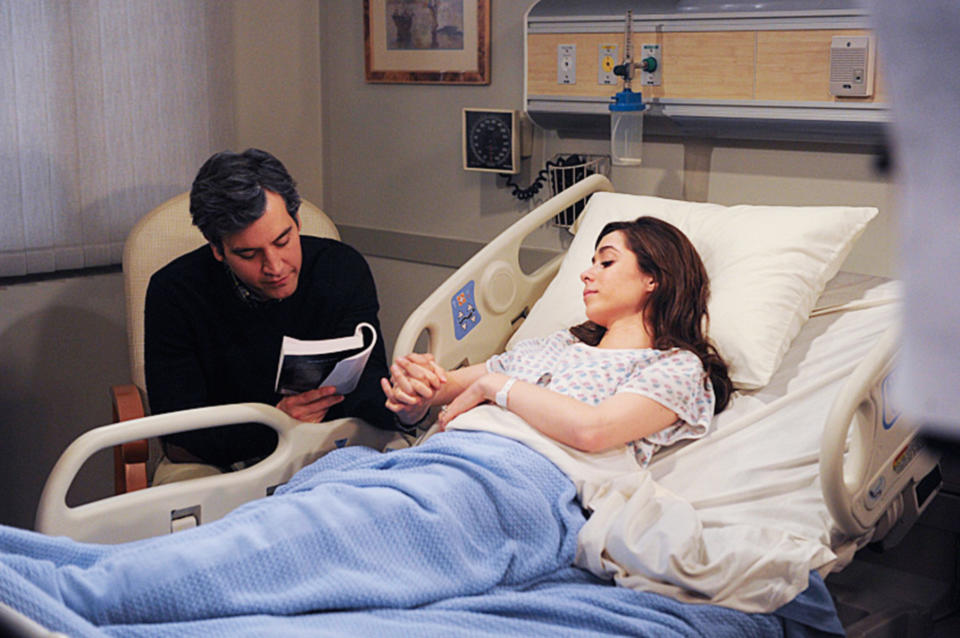 tracy in a hospital bed while ted sits by her side and reads to her