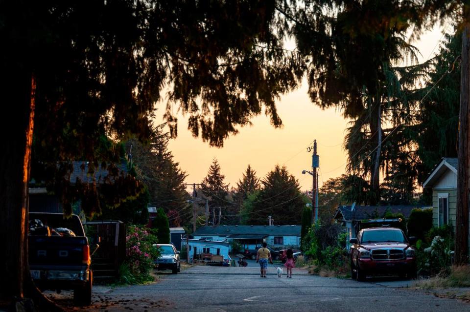 Una madre y su hija pasean a su perro al atardecer por Meridian Estates el miércoles 27 de julio de 2022 en Puyallup, Washington.