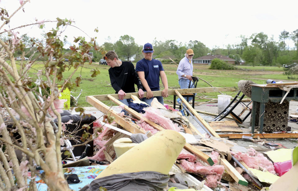 Riley Carter, left and Thomas Boles, center help Jerry Whitaker, right clean up the remains of his brothers house on Seely Drive outside of Hamilton, Miss. after a storm moved through the area on Sunday, April 14, 2019. (AP Photo/Jim Lytle)