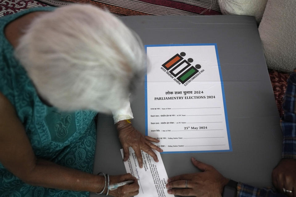 An elderly woman signs a paper after casting her vote at home, in New Delhi, India, Friday, May 17, 2024. To encourage and assist elderly persons to cast their votes, the Election Commission of India initiated the home voting facility for the ongoing general parliamentary elections. (AP Photo/Manish Swarup)