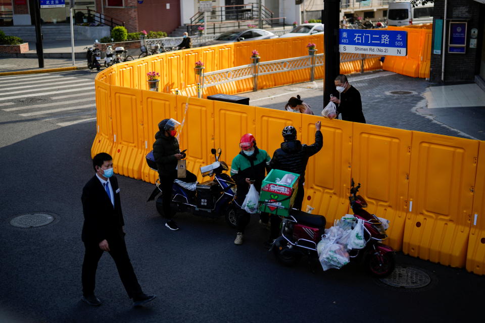 A delivery worker passes food to a man over the barriers of an area under lockdown amid the coronavirus disease (COVID-19) pandemic, in Shanghai, China March 23, 2022. REUTERS/Aly Song