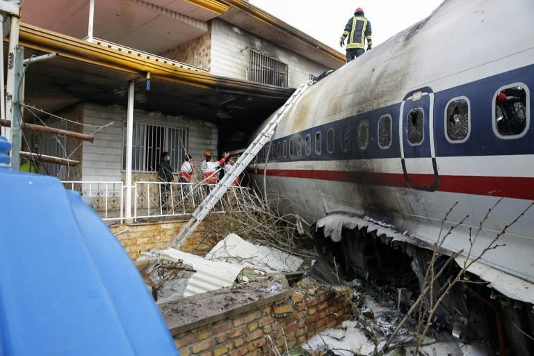 Rescuers examine a Boeing 707 cargo plane that crashed into a residential complex near the Iranian capital Tehran with at least 10 people onboard on January 14, 2019