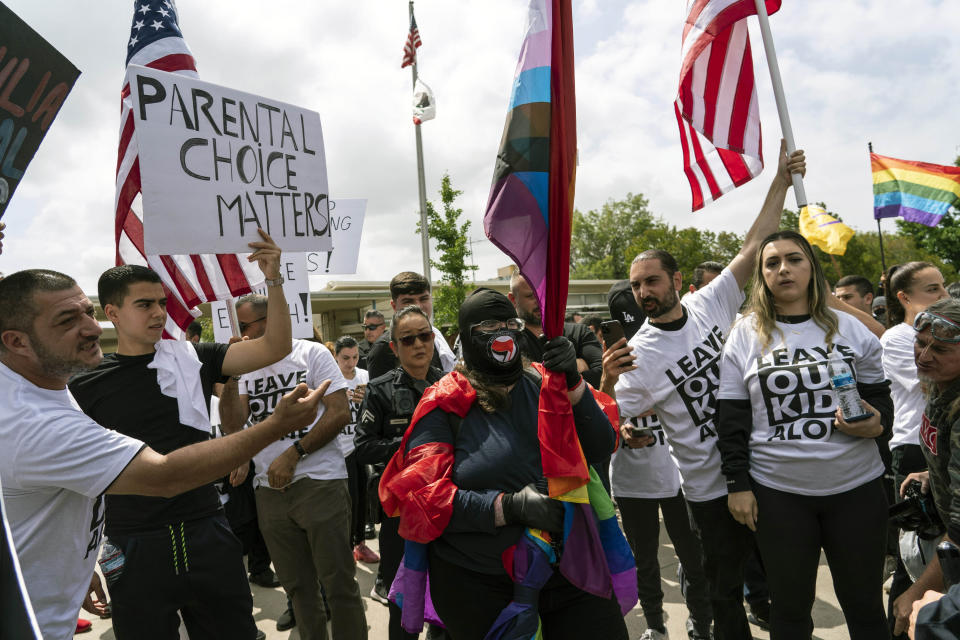 A woman draped in Pride flags is surrounded by people protesting a planned Pride month outside Saticoy Elementary School in Los Angeles, Friday, June 2, 2023. Police officers separated groups of protesters and counter protesters Friday outside a Los Angeles elementary school that has become a flashpoint for Pride month events across California. (AP Photo/Jae C. Hong)