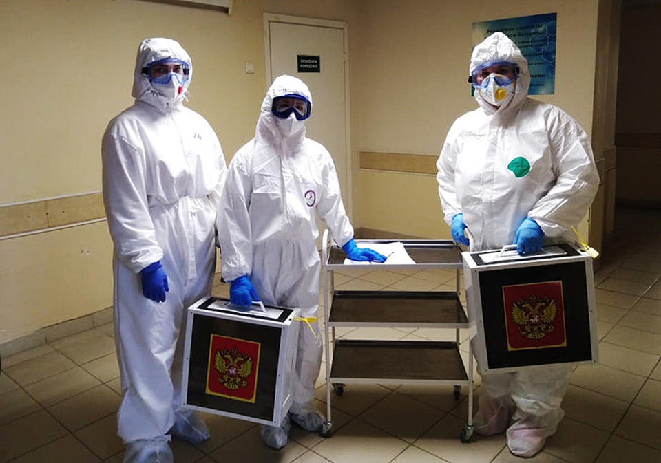 Medical workers wearing protective gear hold ballot boxes pose for a photo prior to go into the red zone to help to coronavirus patients to attend the voting during the Parliamentary elections in Voronezh, Russia, Sunday, Sept. 19, 2021. From the Baltic Sea to the Pacific Ocean, Russians across eleven time zones voted Sunday on the third and final day of a national election for a new parliament, a ballot in which the pro-Kremlin ruling party is largely expected to retain its majority after months of relentless crackdown on the opposition. (AP Photo)