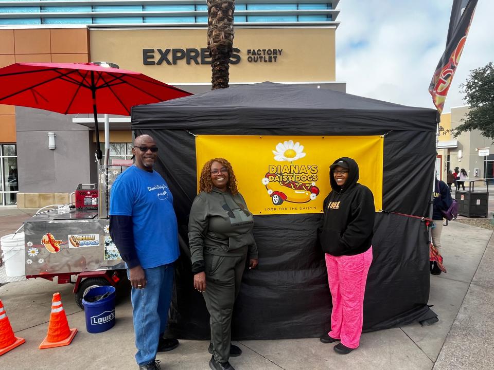 From left to right, Ronald Jones, Zena Jones and Zhane Jones sell hot dogs and hot links at Tanger Outlets on Dec. 23, 2023.