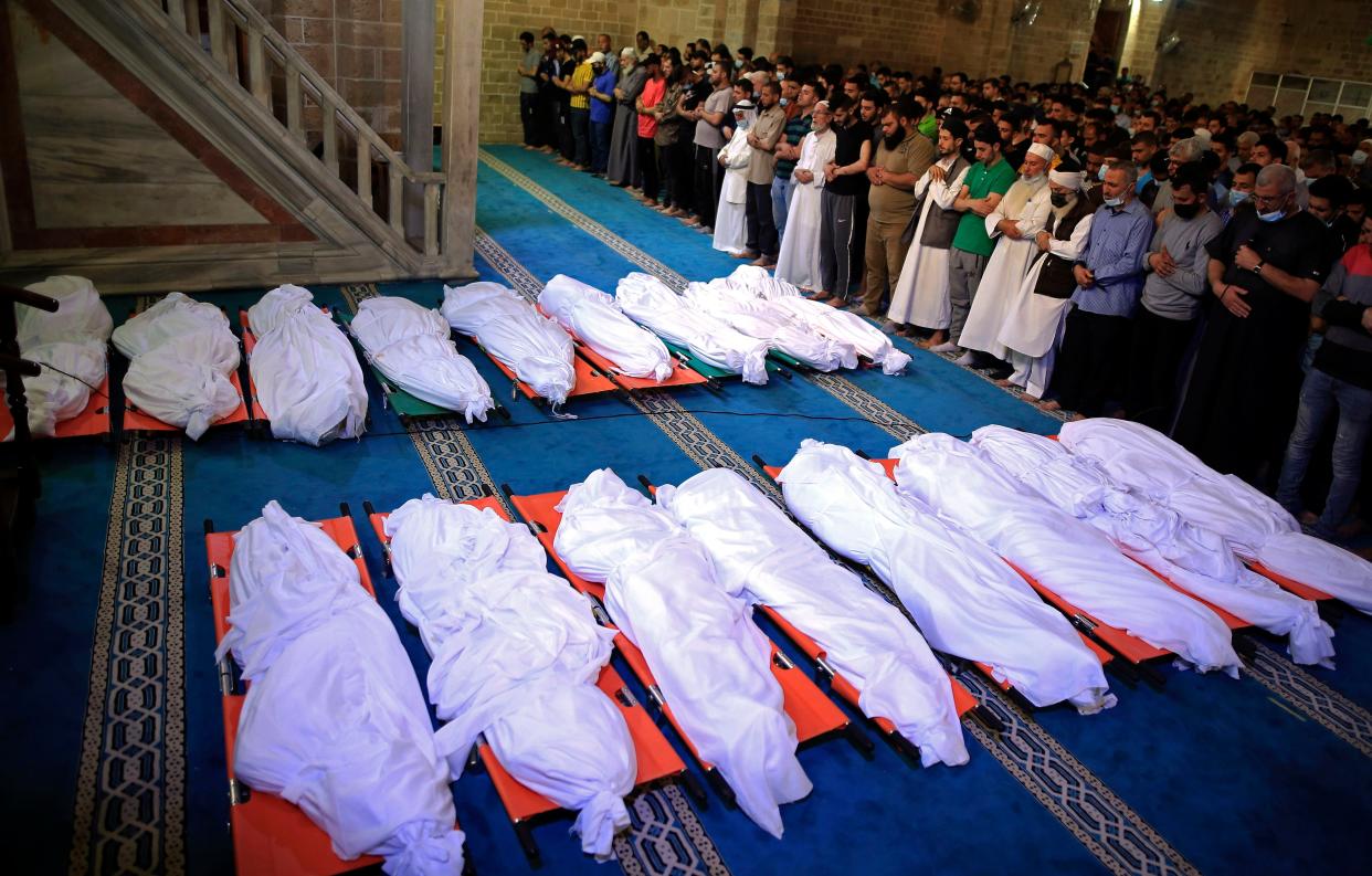 Mourners pray over the bodies of 17 Palestinians who were killed in overnight Israeli airstrikes in Gaza City, Sunday, May 16, 2021.