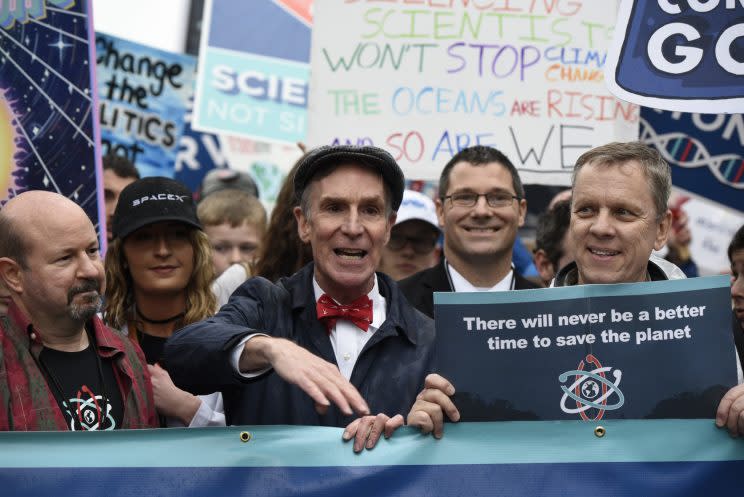 Bill Nye surrounded by people holding signs at the March for Science 