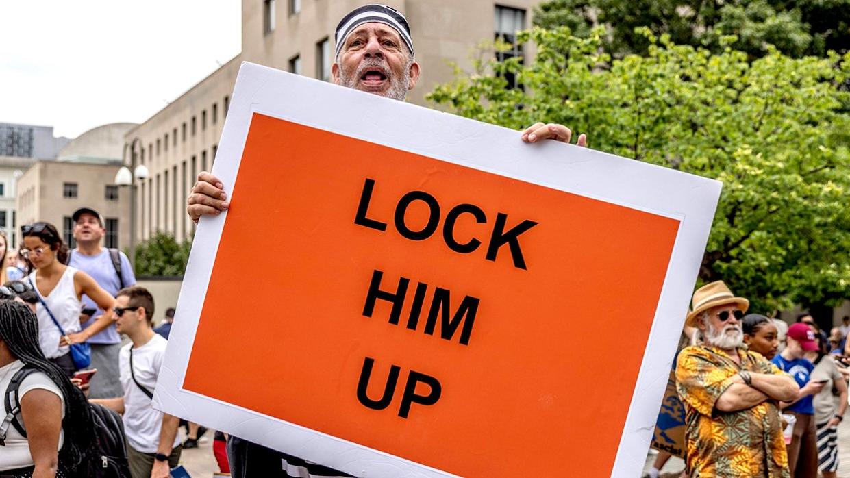 Donald Trump protester Lock Him Up sign prisoner outfit