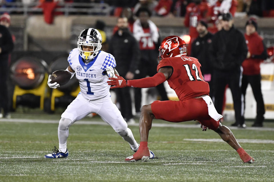 Kentucky wide receiver Wan'Dale Robinson (1) attempts to avoid Louisville defensive back Qwynnterrio Cole (12) during the first half of an NCAA college football game in Louisville, Ky., Saturday, Nov. 27, 2021. (AP Photo/Timothy D. Easley)