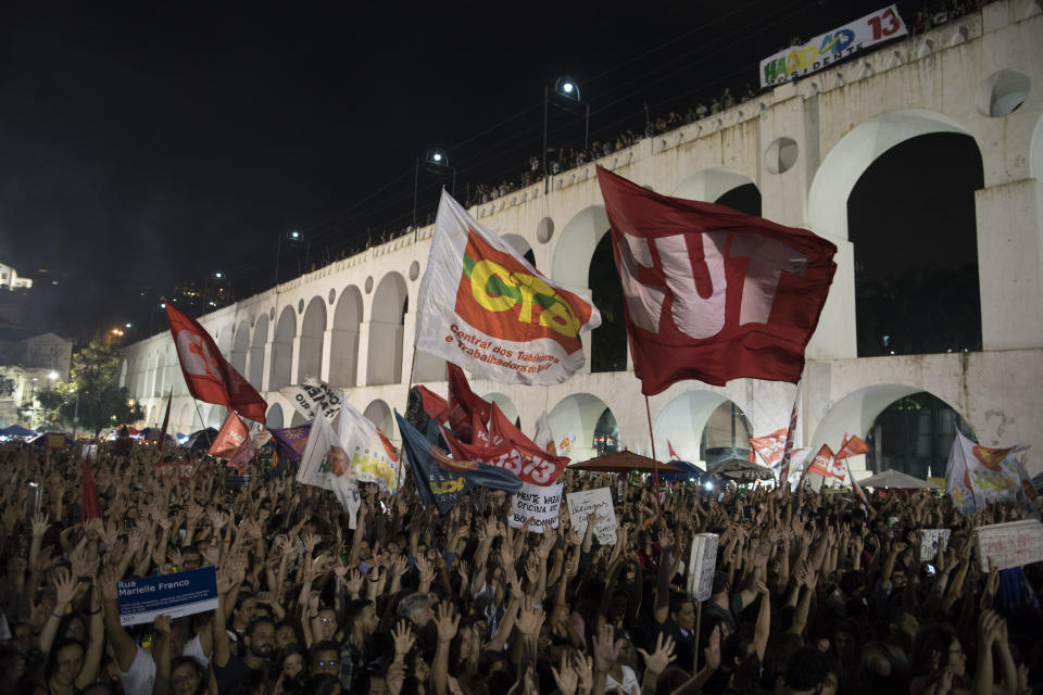 FILE - In this Oct. 23, 2018 file photo, people gather next to the Carioca Aqueduct, also know as Arcos da Lapa, during a campaign event with popular Brazilian artists and musicians in support of the Workers' Party presidential candidate Fernando Haddad, in Rio de Janeiro, Brazil, Tuesday, Oct. 23, 2018. Haddad has put the suffering of Brazilians during a protracted recession at the center of his campaign, blaming much of the downturn on President Michel Temer’s reforms, even though the economy began to tank while the previous Workers’ Party president was still in power. (AP Photo/Leo Correa, File)