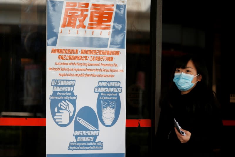 Woman wears a mask as she walks past a health warning poster at hospital, in Hong Kong