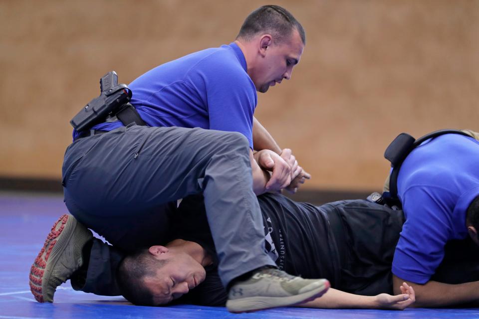 In this June 4, 2020, photo, Brandon Wilson, upper left, an instructor at the Washington State Criminal Justice Training Commission facility in Burien, Washington, restrains fellow instructor Ben Jia, lower left, during a demonstration for The Associated Press on takedown and restraint techniques taught to law enforcement officers.