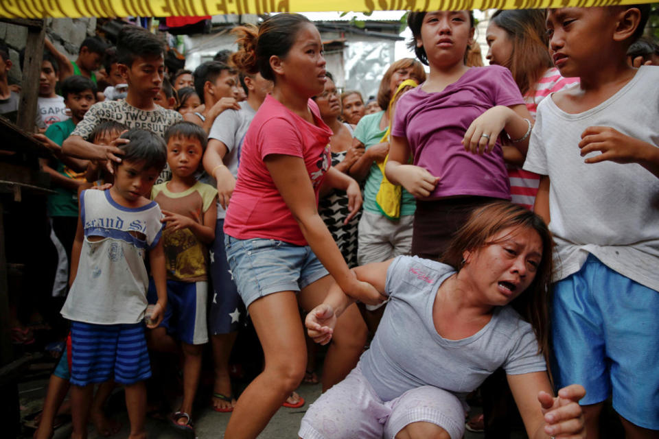 Janeth Mejos reacts as the body of her father is taken out after he was killed in a police raid Manila