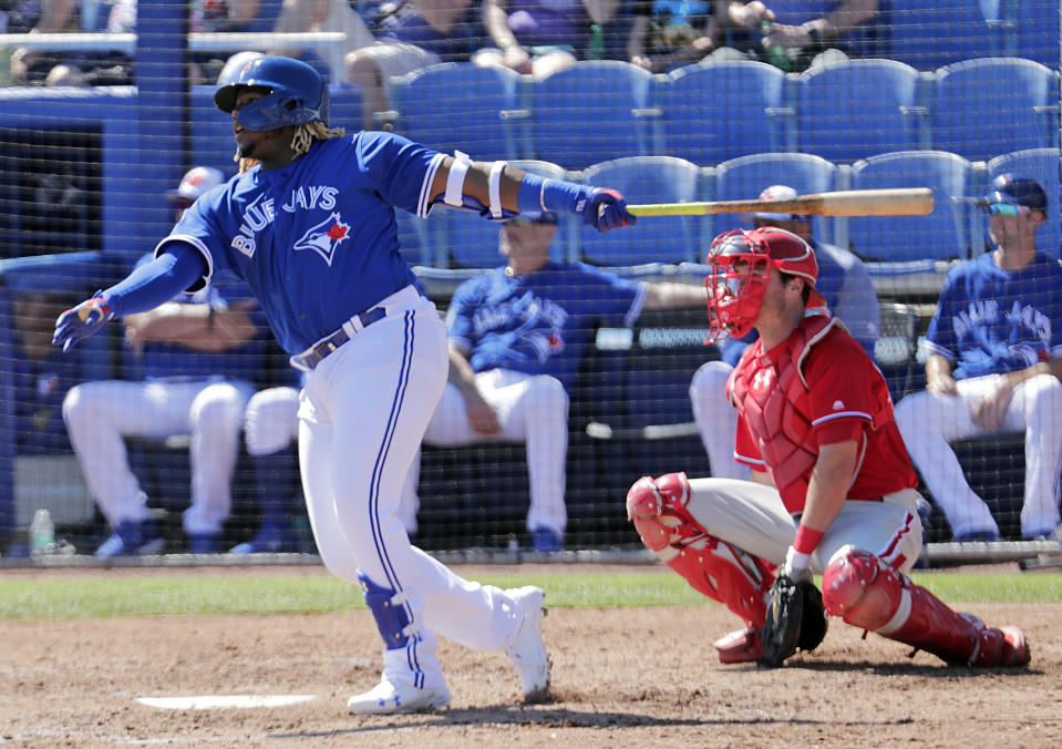 FILE - In this Feb. 28, 2019, file photo, Toronto Blue Jays' Vladimir Guerrero Jr., left, follows through with a double as Philadelphia Phillies catcher Andrew Knapp looks on in the third inning of a spring training baseball game in Dunedin, Fla. The Toronto Blue Jays will promote top prospect Vladimir Guerrero Jr. before their game against the Oakland Athletics, on Friday, April 26. (AP Photo/Lynne Sladky, File)