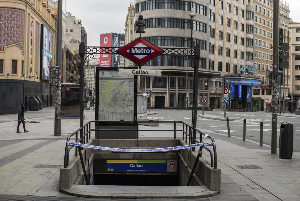 FILE - In this April 14, 2020 file photo, a man walks past a closed subway station during the lockdown to combat the spread of coronavirus in downtown Madrid, Spain. Nervous travelers, spotty air service, health risks _ the battered global tourism industry is facing unprecedented uncertainty in the wake of the new coronavirus. Millions of workers are laid off or furloughed, and it will likely take years for the industry to get back to the strong demand it was seeing just six months ago. (AP Photo/Manu Fernandez, File)